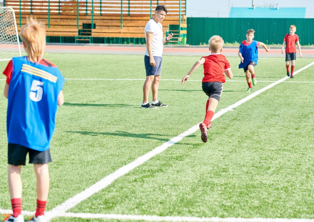 Children doing sports in schools and playing football on a field