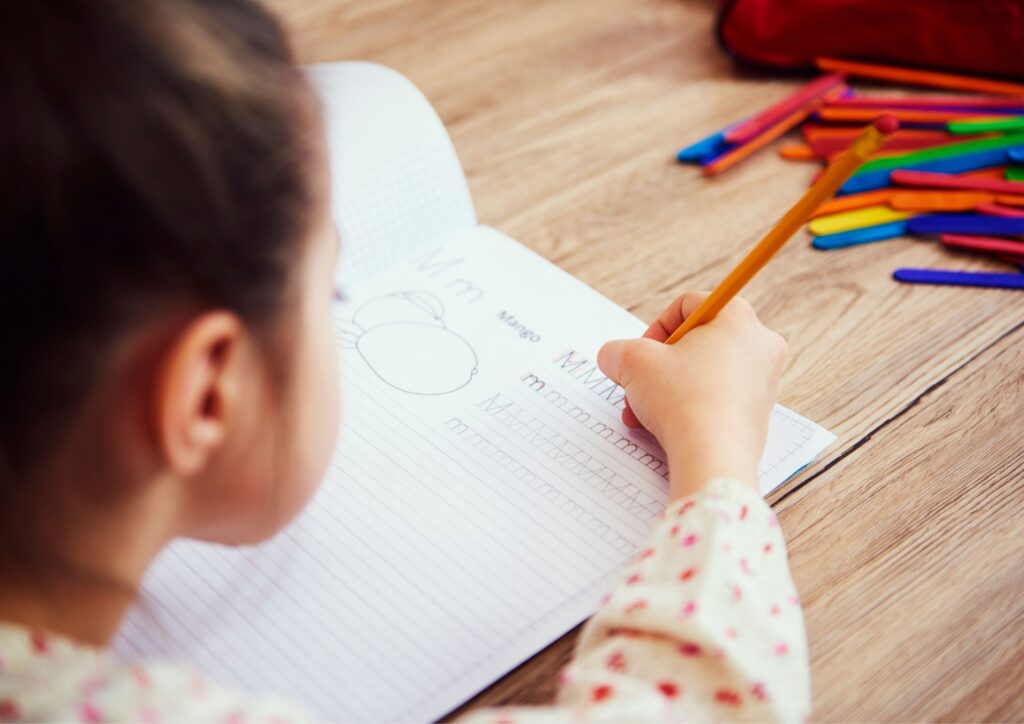 A girl writes on paper at a study space in her room