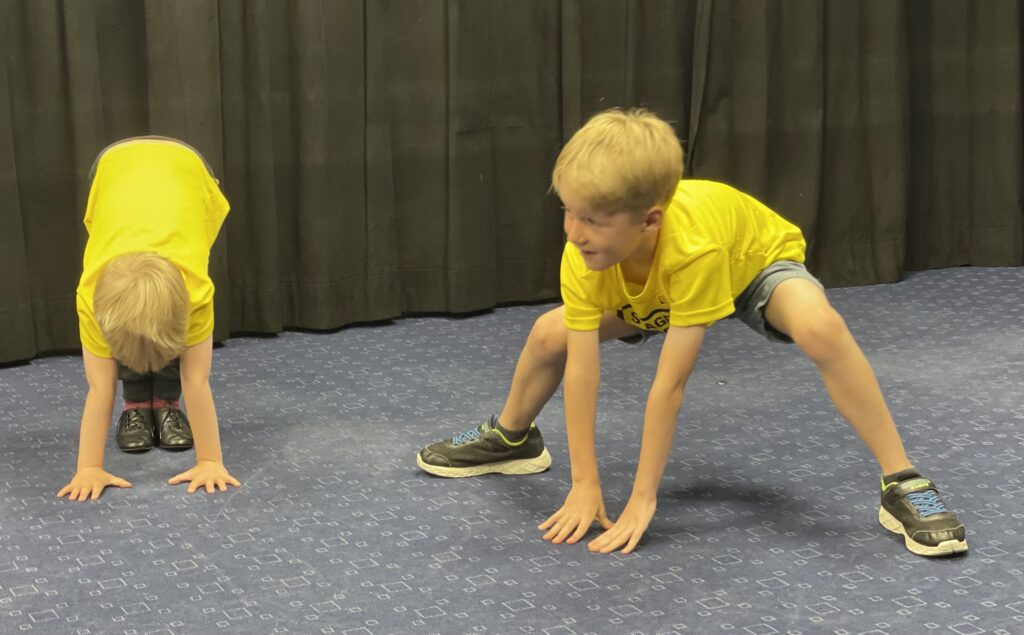 Six year old in a yellow t.shirt with a black background taking part in a Stagecoach performing arts class