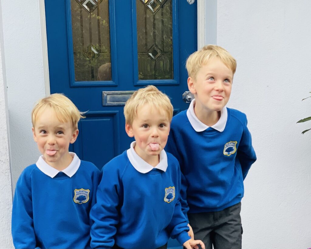 Three boys in uniform on the first day of school when the youngest child is starting school