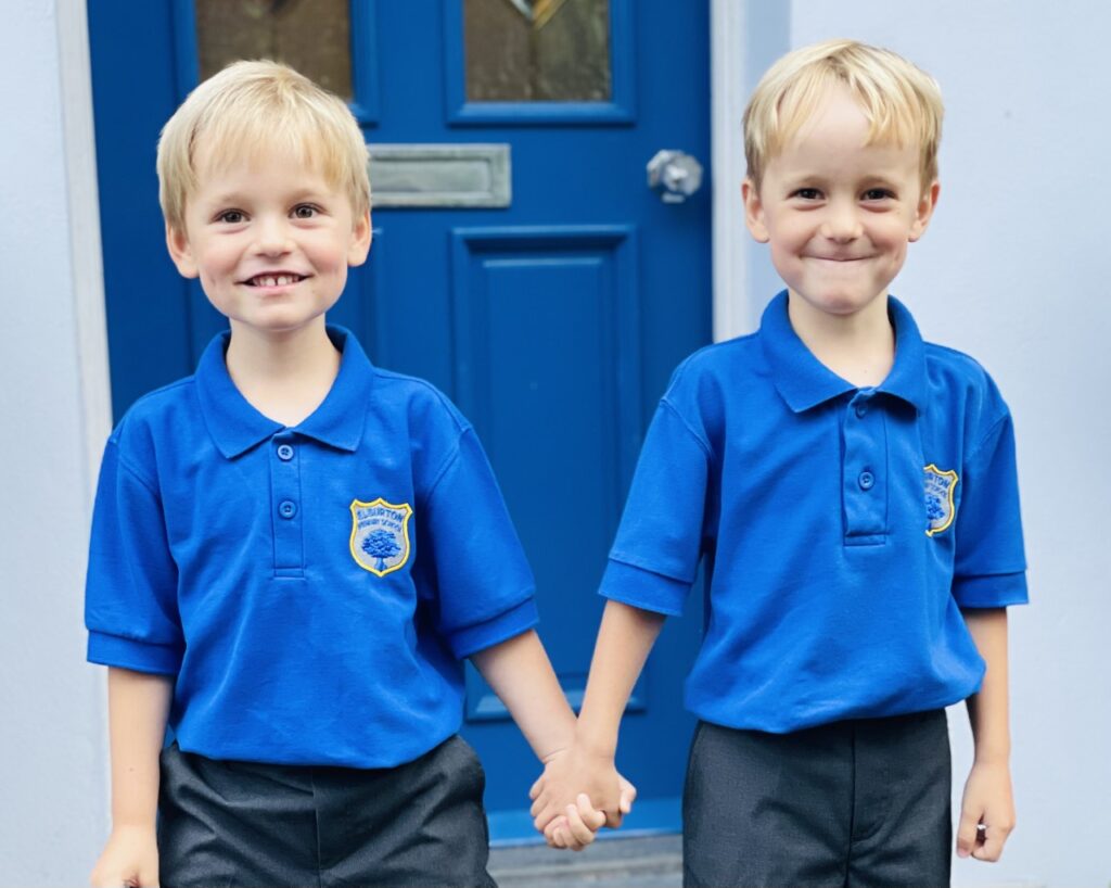 Four year old twin brothers starting school in school uniform on the doorstep