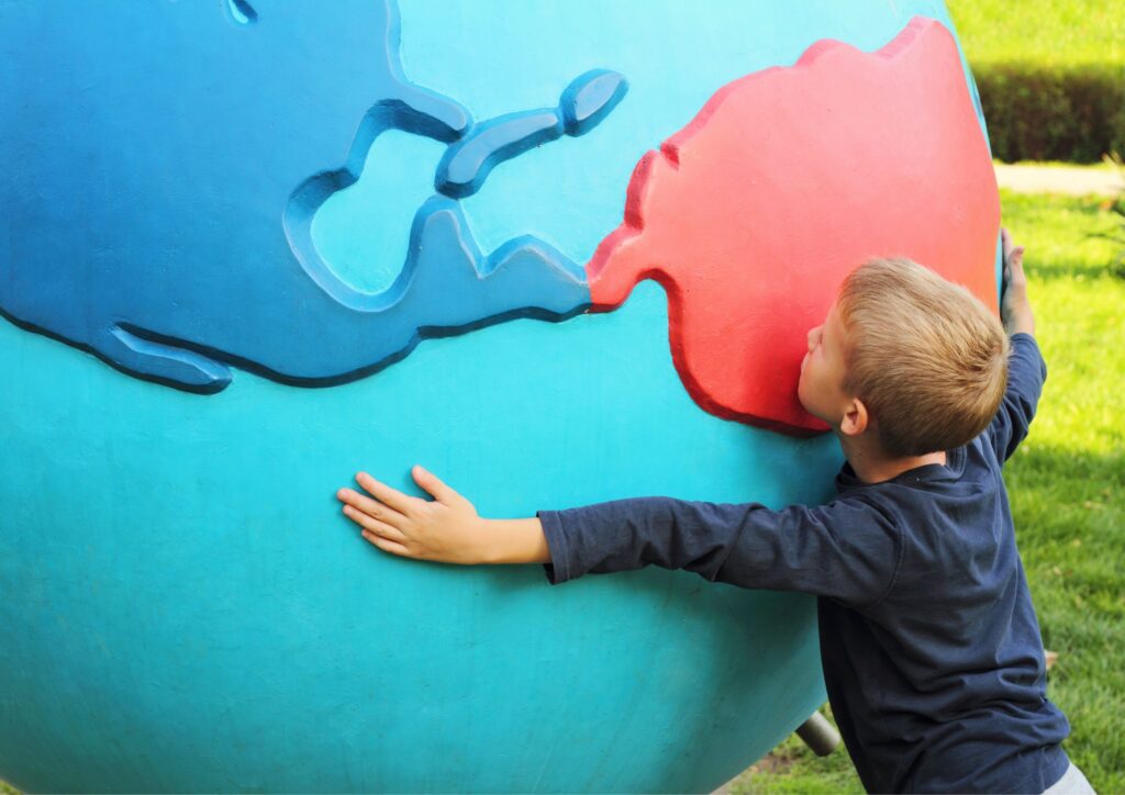 Little boy hugs a huge model of planet Earth