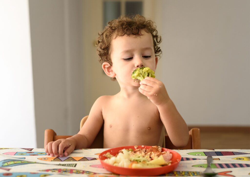 A toddler eats brocoli with his fingers to tackle an iron deficiency