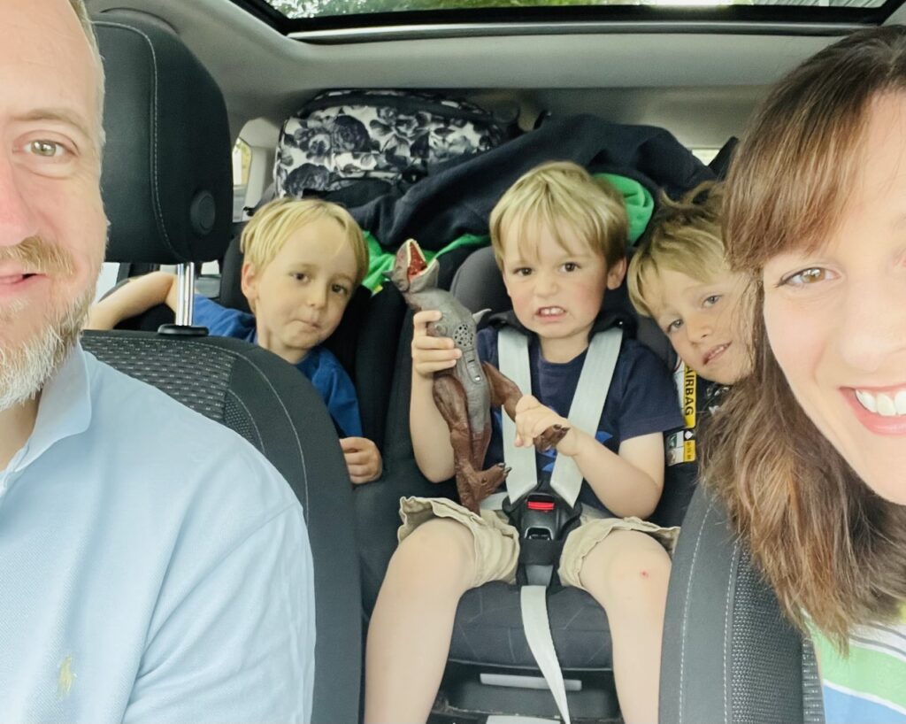 Three boys in back of car and parents in front, trying to keep kids entertained on car journeys