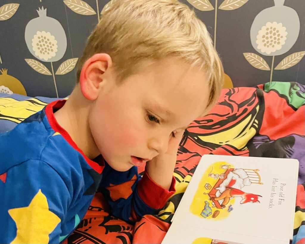 Four year old reading a book as part of his bedtime routine and how to boost your child's imagination