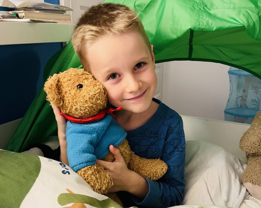 Little boy with a teddy in bed as part of his bedtime routine