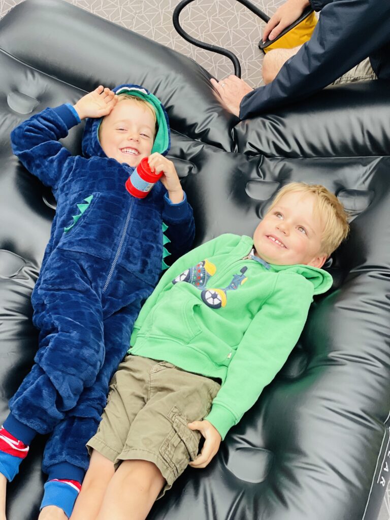 Two boys on an airbed camping for a post about how to entertain kids during the summer holidays