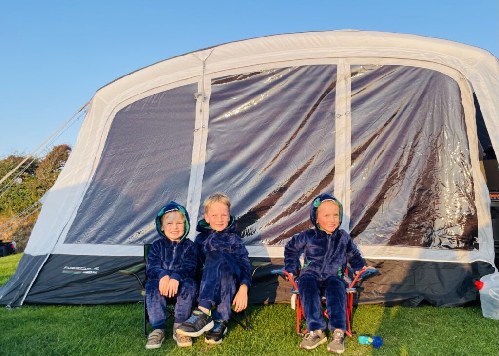 Boys wearing onesies to keep warm by a tent for how to make camping with kids easier