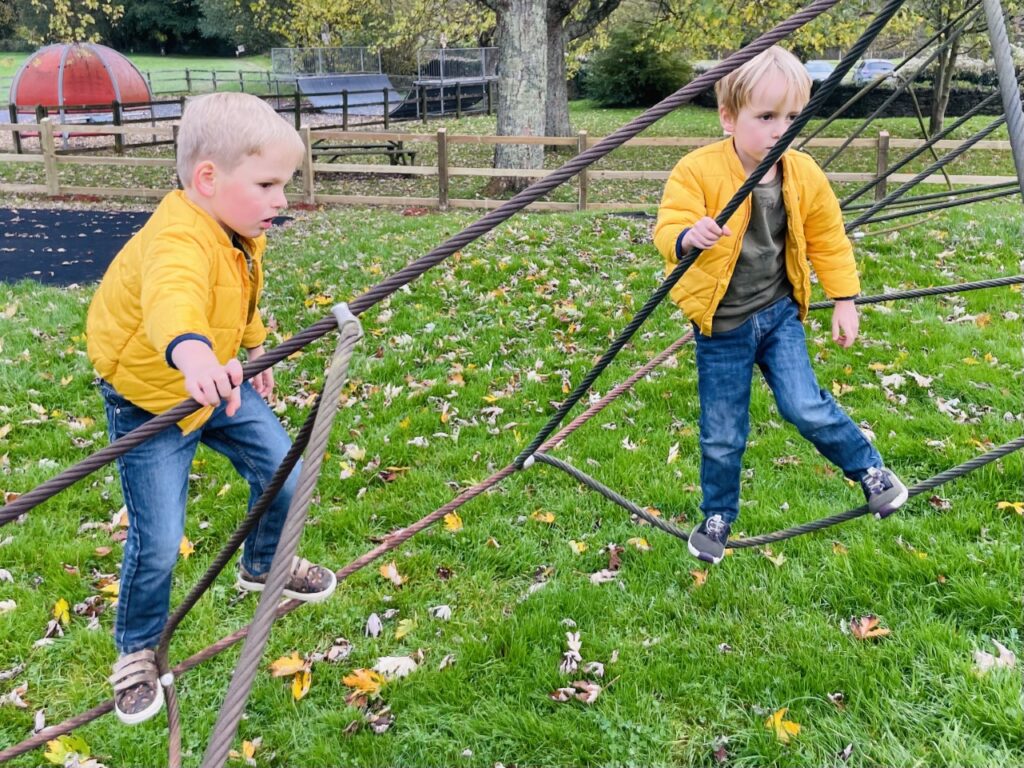 Twins on a rope climbing frame at the park