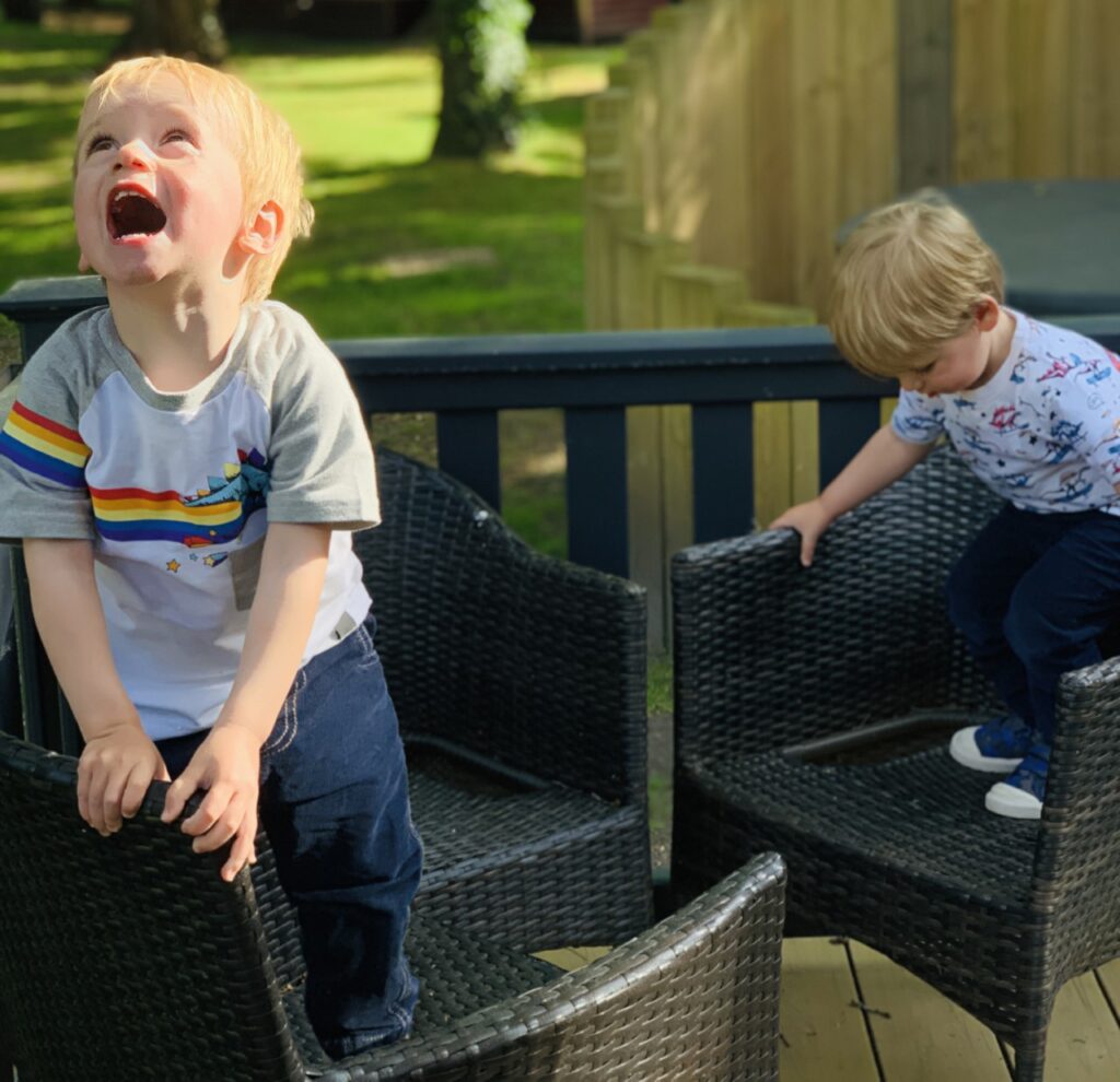 Twins climb on chairs whilst doing gross  motor play