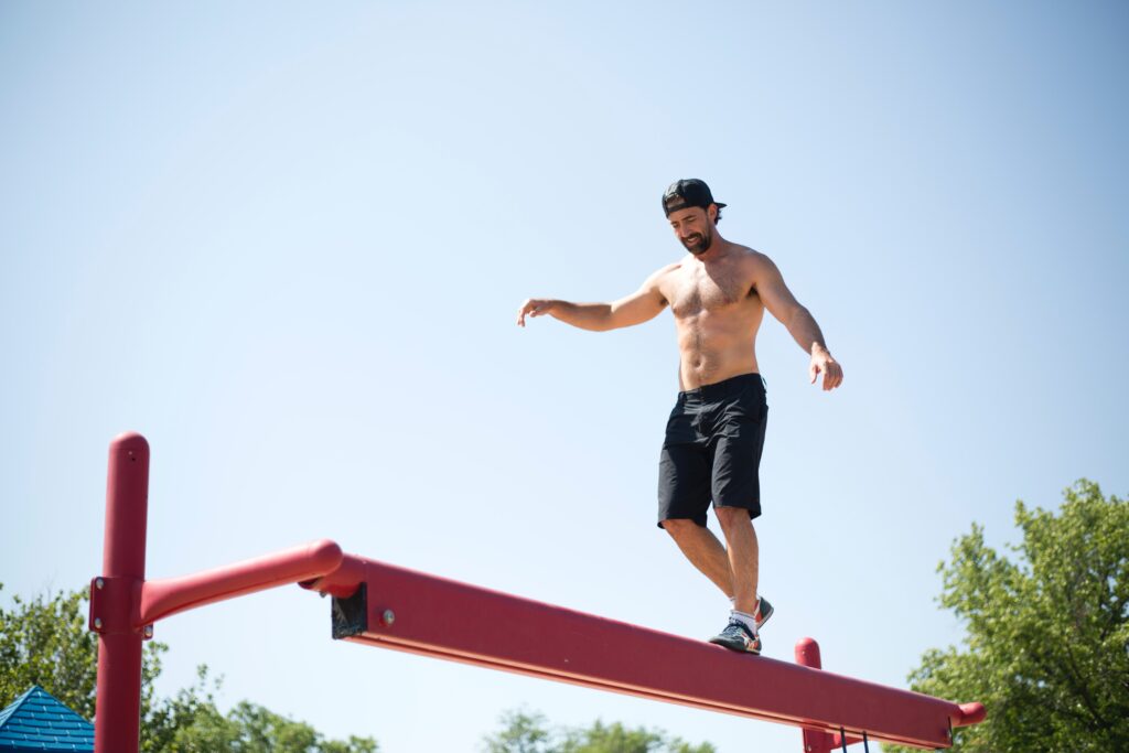 Getting fit while the children play at a play park and a man balances on play equipment