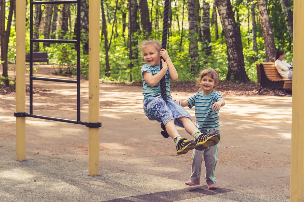 Two children on a zip wire at a park