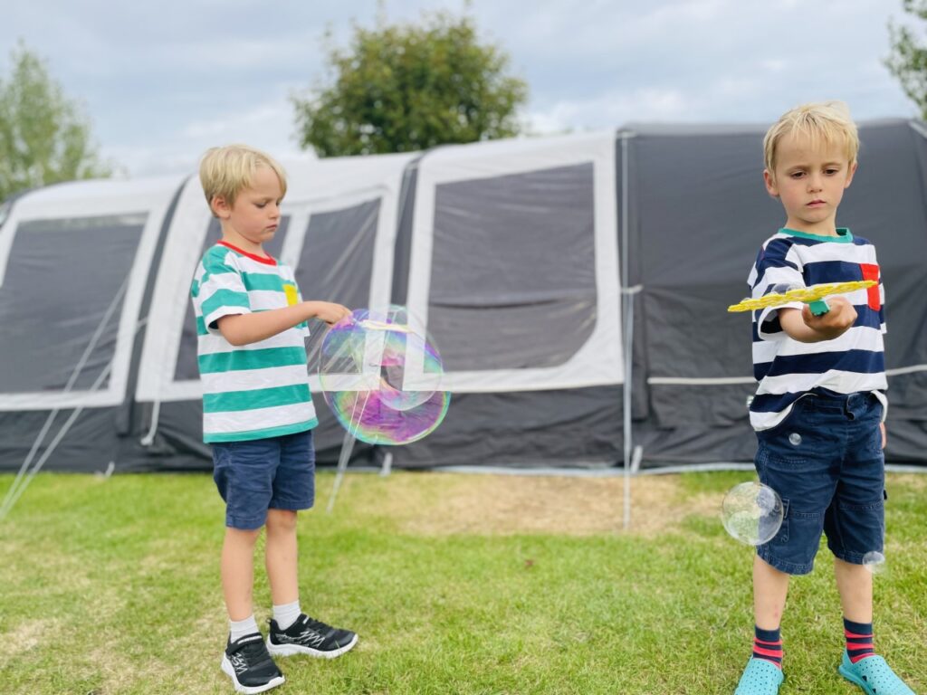 Twin brothers playing with bubbles whilst camping