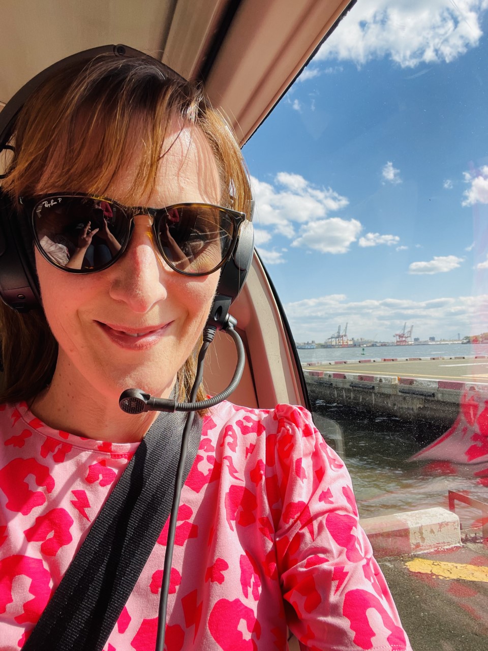A woman in a pink top is in a helicopter about to fly over Manhattan