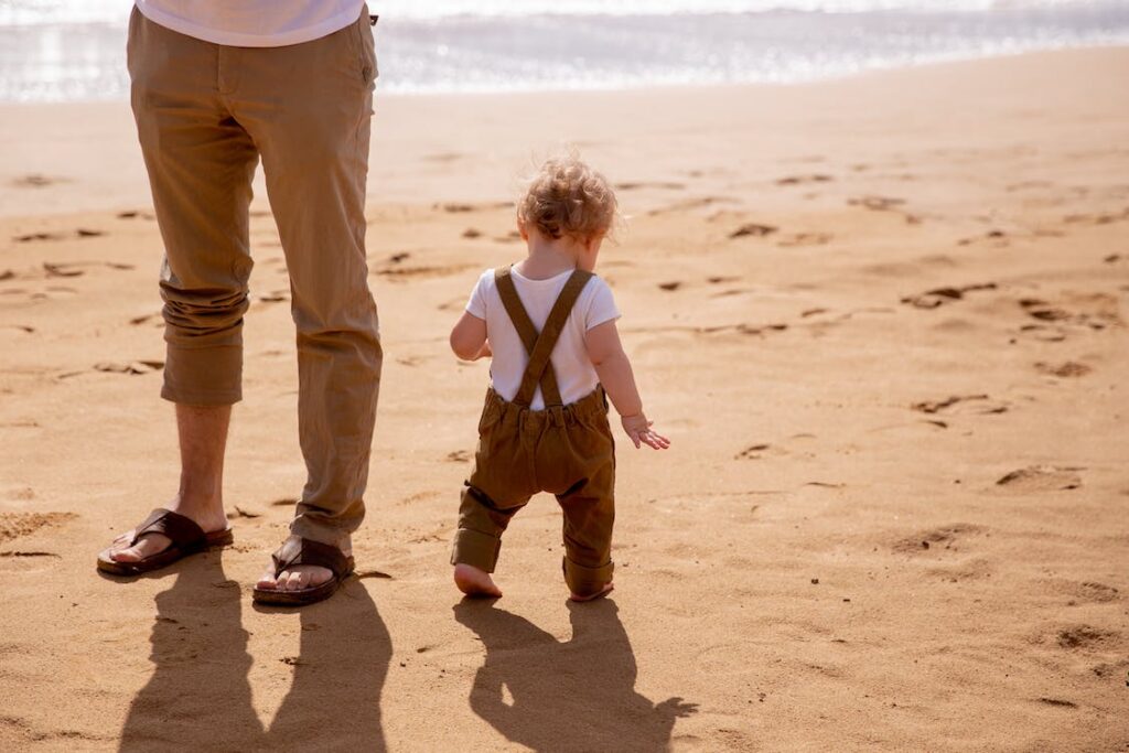 A toddler and dad on a beach, on a holiday to Spain with kids