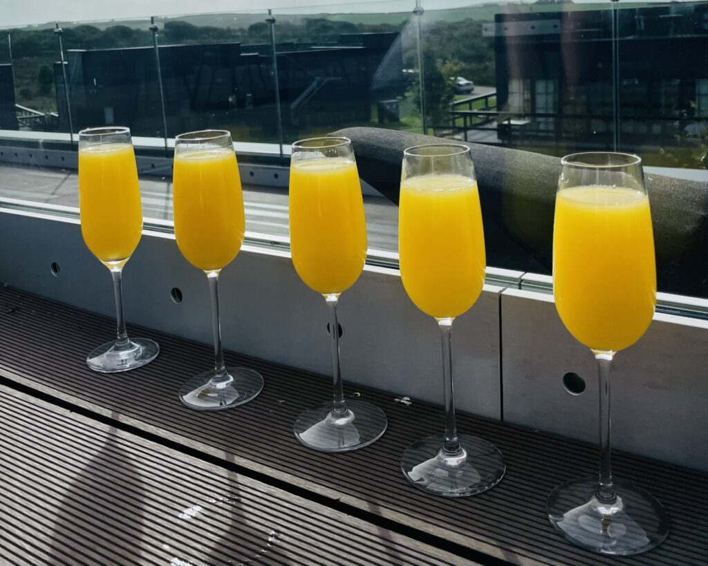 5 glasses of bucks fizz lined up on the balcony at Retallack