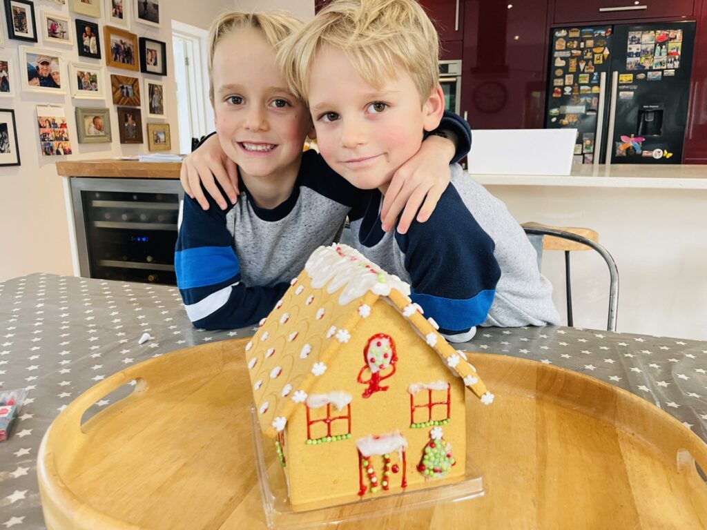Twin brothers making a gingerbread house as one of several Christmas traditions