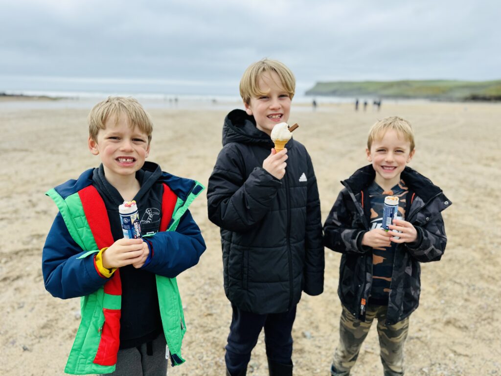 Three boys eating ice cream on Polzeath beach